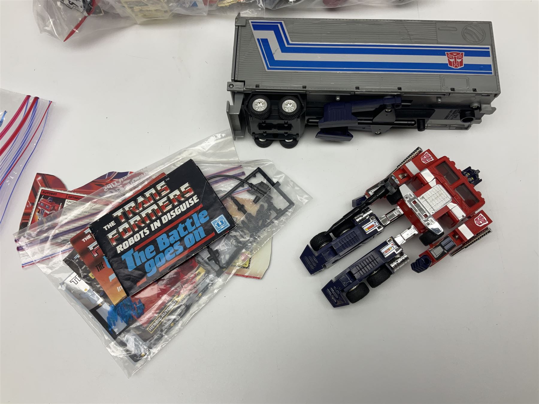 Four 1980sTransformer G1 - Optimus Prime 1984; DinoBot Sludge (Diplodocus) 1984; Cyclonus 1986; and Runamuck 1986; with paperwork; seven Bandai Robo Machines Robots/Transformers; almost fully stocked Panini Sticker album; two annuals; three comics; two posters; and Ladybird story book