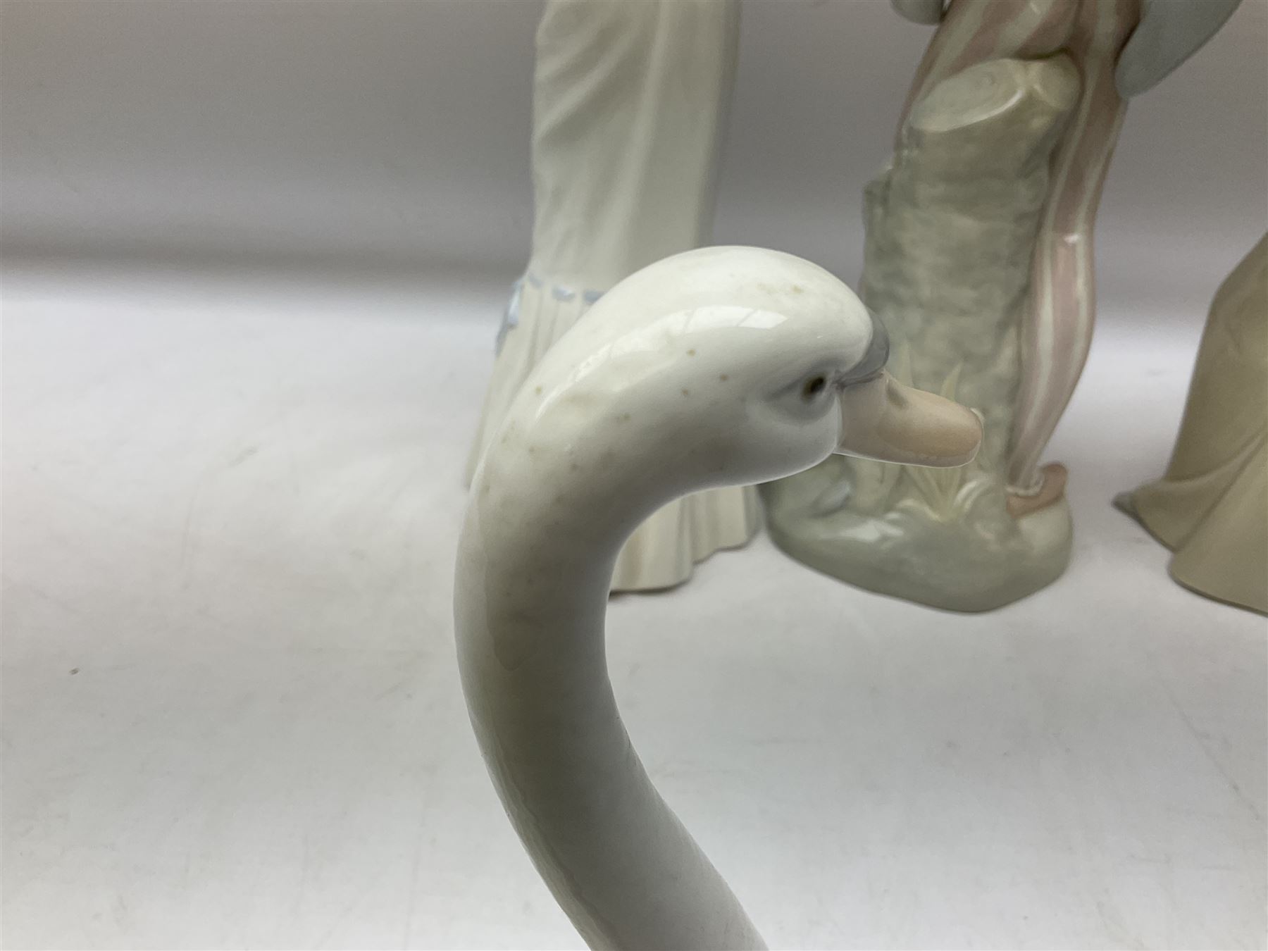 Lladro 'Walk With the Dog' figure no. 4893, together with Lladro swan figure, Porceval figure of a gentleman with a bird perched upon his hand and a further of a lady with flowers beside a basket, all with marks beneath, tallest H40cm