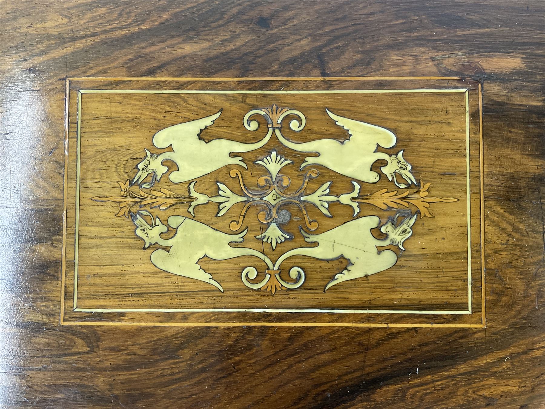 Edwardian inlaid mahogany games or work table, rectangular fold-over top inlaid with stylised dragon ivorine decoration and stringing, fitted with one long flanked by four small drawers over sewing compartment drawer, raised on square tapering supports with castors