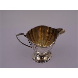 Edwardian silver cream jug, of fluted helmet form, with angular handle and upon shaped foot, hallmarked Birmingham 1905, maker's mark indistinct, together with a set of six Edwardian silver teaspoons and a pair of sugar tongs, all with scrolling embossed decoration and engraved monogram, hallmarked Joseph Rodgers & Sons, Sheffield 1903, within tooled leather fitted case, jug including handle H9cm 