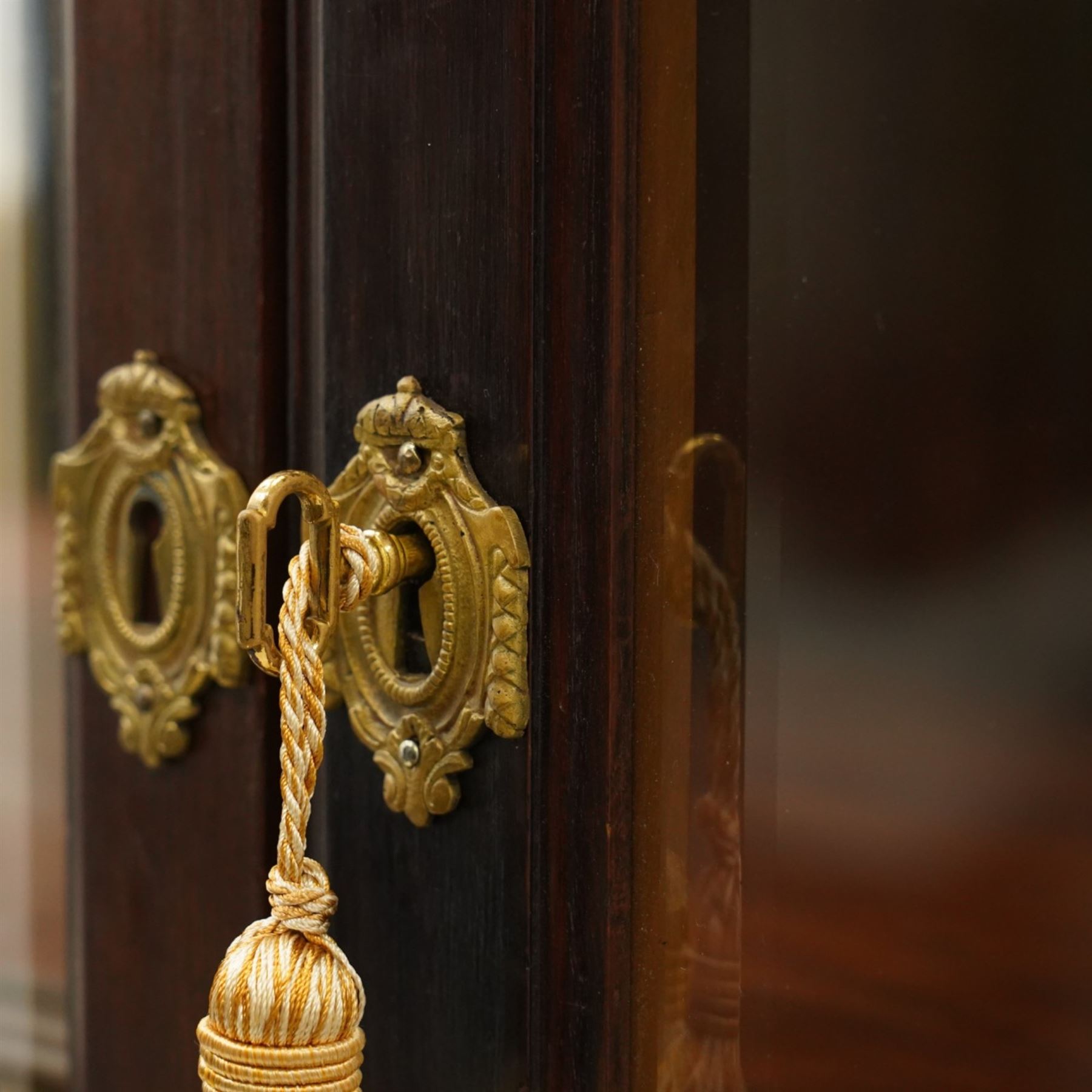 Large and impressive 19th century heavily carved mahogany display cabinet, the ornate pediment carved with a central scalloped and foliate rocaille motif with extending acanthus leaves and egg-and-dart moulding flanked by acanthi finials, over a central cartouche with carved bow-and-arrow motif and trailing scrollwork, the bookcase enclosed by two glazed doors with bevelled glass sides, the base with a gadrooned upper edge over a central rocaille ornament with scrolling acanthus leaves, the panelled frieze with further foliate motifs, raised on large carved snarling lion mask supports with floral garlands and claw feet, united by a concave rectangular platform base with gadrooning egg-and-dart moulding