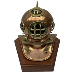 Copper and brass miniature diving helmet upon a wooden plinth, H26cm