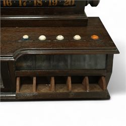 Victorian wall-mounted oak and walnut cased scoreboard,  moulded top, with a name stencilled in the frieze ‘J. Ashcroft, Victoria Street, Liverpool’, the board with chalk panel in the centre for recording scores, sliding panels on both sides for the various games of Billiards and Snooker, two numbered rotating arms with adjustable sliding score keepers, the base section with 5 apertures on each side, and coloured ivory roundels, all with glass front for viewing the tokens inside, with drawers beneath, the centre has a long glass panel for storing billiard balls, circa 1870 This item has been registered for sale under section 10 of the APHA Ivory Act Reference UNEGEBLB
