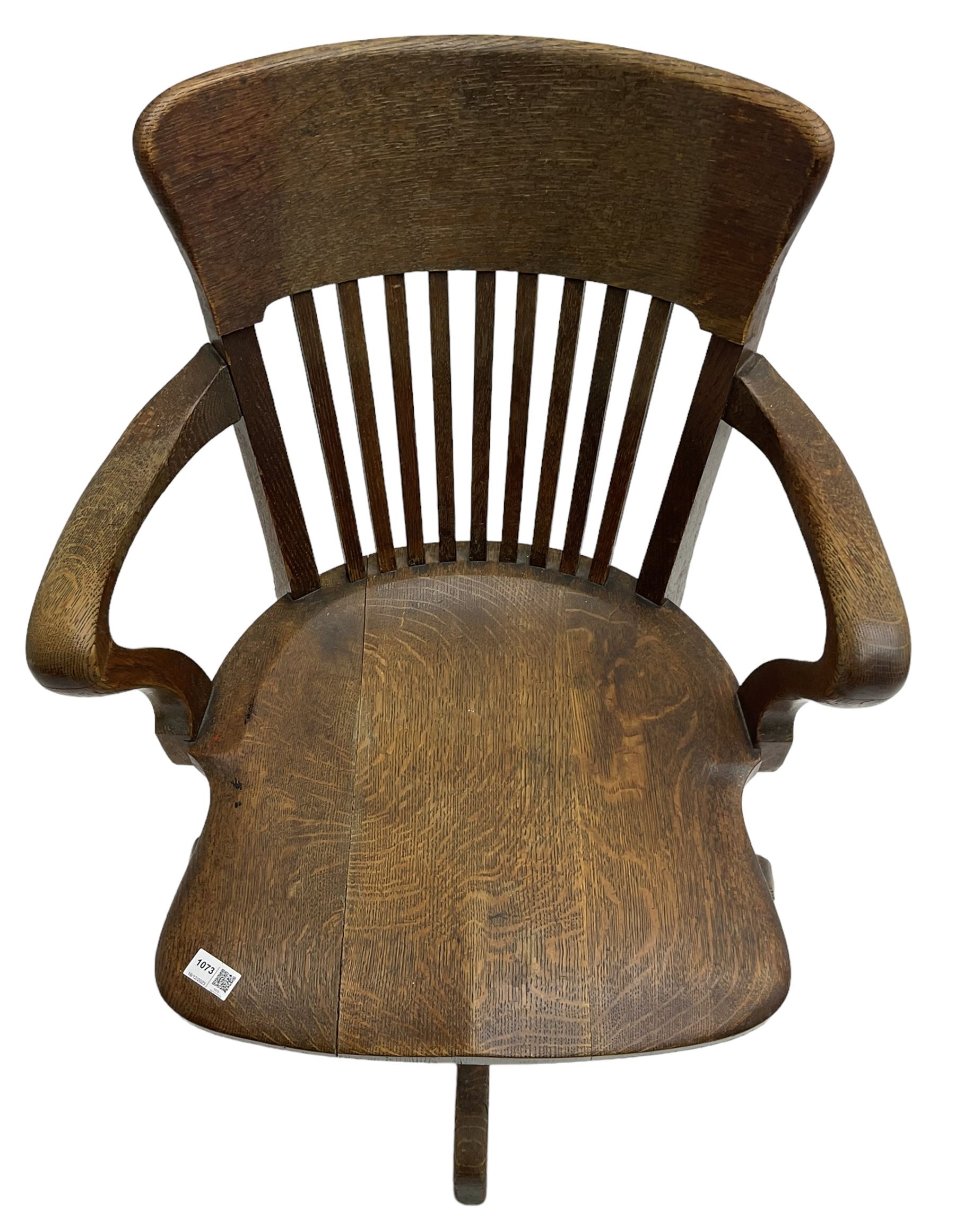 Early 20th century swivel office desk chair, shaped bar back over vertical rails, dished seat, on four splayed supports