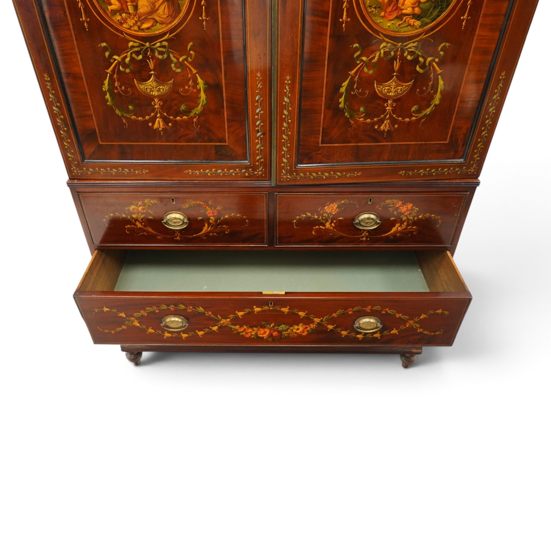 19th century French Louis XVI design mahogany and polychrome painted gentleman's press wardrobe - projecting cavetto cornice with urn and bellflower painted frieze, the twin doors with classical figural medallions surmounted by urns and festoon decoration with scrolling acanthus leaves, enclosing five sliding trays, the base fitted with two short over three long cock-beaded drawers, the facias painted with interlocking swags and garlands of bouquets with recumbent lion brass handle-plates, lower reeded edge on turned feet