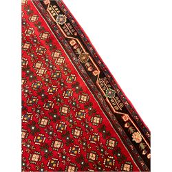North West Persian crimson ground Bidjar runner, the field decorated with rows of stylised flower head motifs, indigo ground border with trailing design decorated with plant motifs, within guard stripes