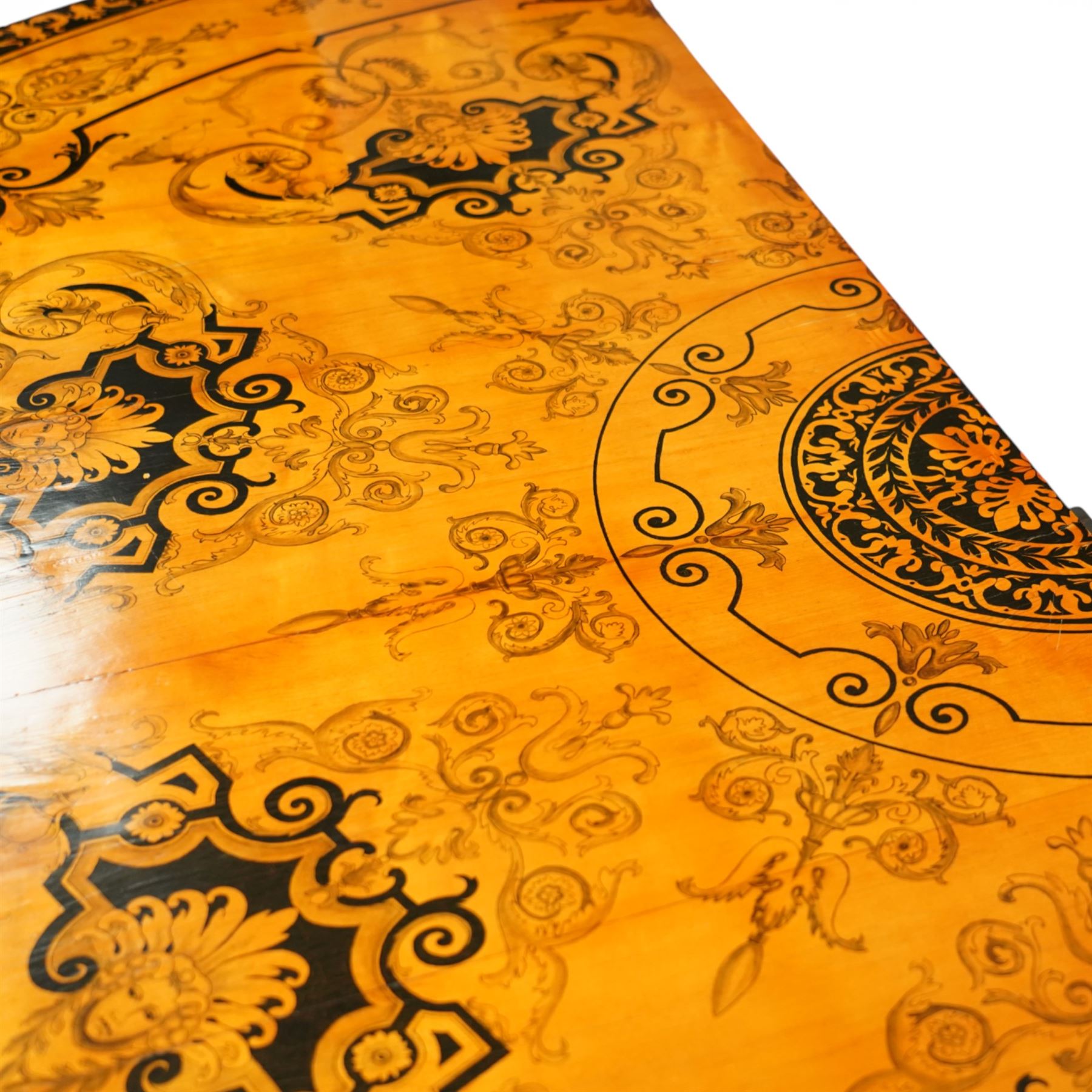 20th-Century Louis XVI-Style satinwood and penwork circular table or pair of console tables, the circular quarter-veneered top decorated in penwork with a central classical mask head motif within scrolling foliate and anthemion ornament on a contrasting black ground, above a conforming frieze decorated with Greek key-type scrolls. Raised on square tapering legs, each with an upper block panel decorated with compass-star motifs.