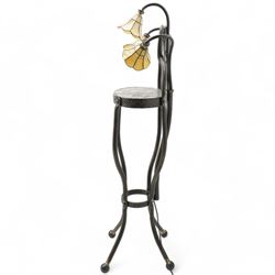 James Godbold - Art Nouveau blacksmith-made wrought iron floor standing lamp table, the round etched metal tabletop decorated with swirling foliage motifs, crowned by three Tiffany design amber glass shades mounted on curved iron stems, raised on four splayed supports united by circular stretcher and terminating in ball feet