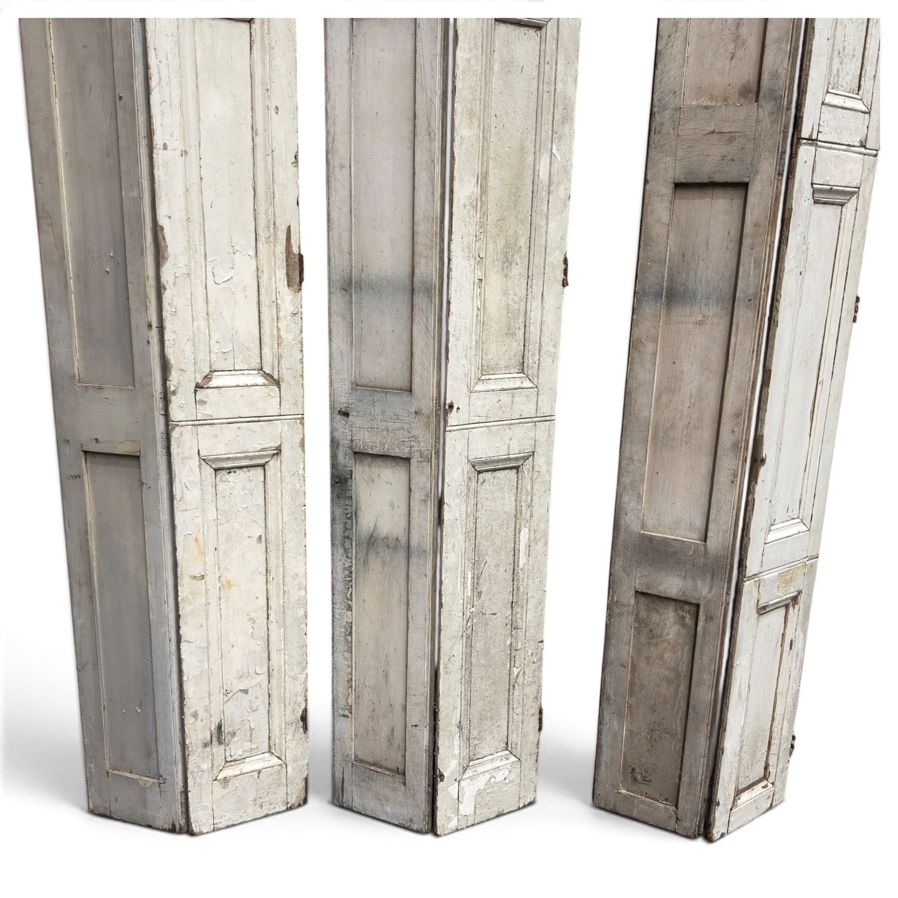 Set of three French 19th century painted pine folding window shutters of tall form, each comprising two hinged leaves with three graduated raised and fielded panels, in antique cream-painted finish