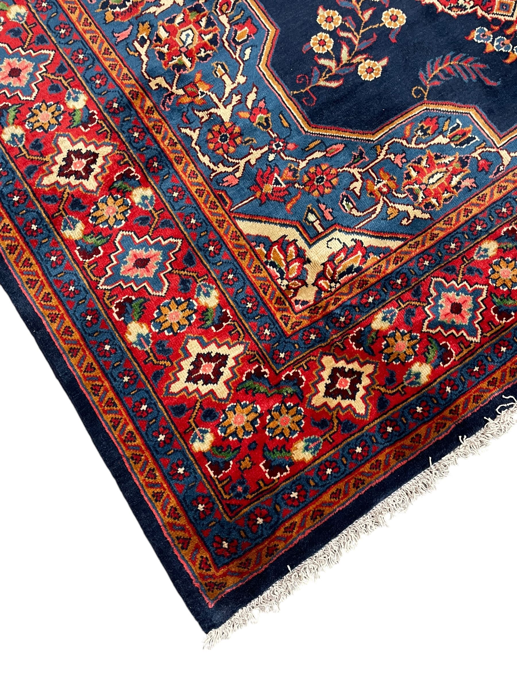 Persian Veis indigo ground carpet, the field with large pole medallion decorated with Herati motifs and surrounded by floral sprays, crimson ground border with repeating cross motifs and stylised flower heads, within guard stripes 