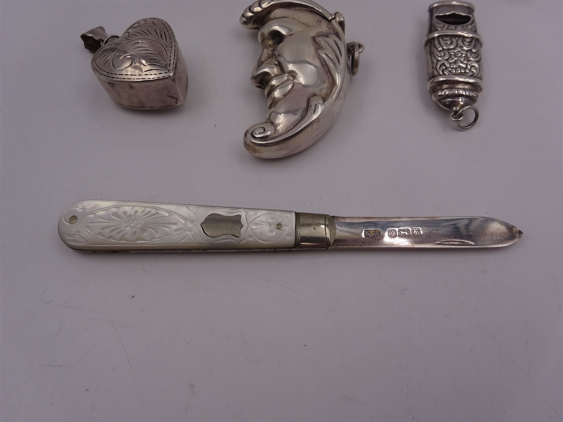 Group of novelty silver items, comprising man in the moon vesta case, perfume pendant and a whistle, unmarked but test silver, together with a mother of pearl handled silver fruit knife, silver cigarette case, both hallmarked and a small quantity of silver threepences