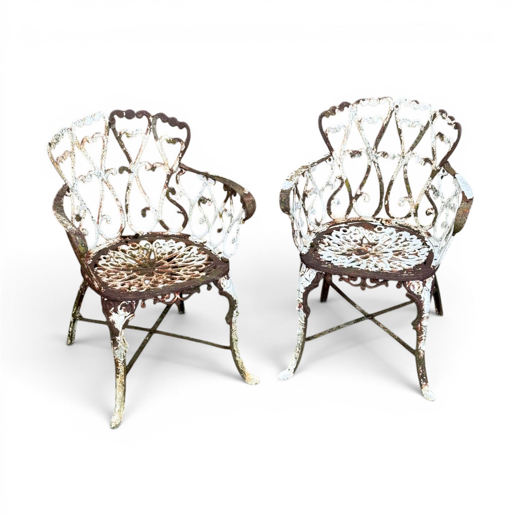 Pair of late 19th century painted cast iron garden chairs, open scroll and heart backs, ornate circular seat, raised on cabriole legs with X stretcher