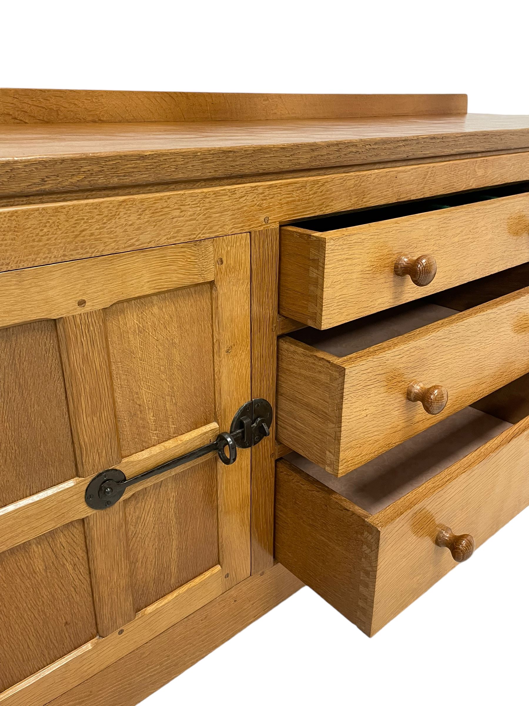 Mouseman - oak dresser, rectangular adzed top with raised back over three central drawers and two flanking cupboards, enclosed by panelled doors with wrought metal fixtures, the canted upright carved with mouse signature, on octagonal feet, by the workshop of Robert Thompson, Kilburn