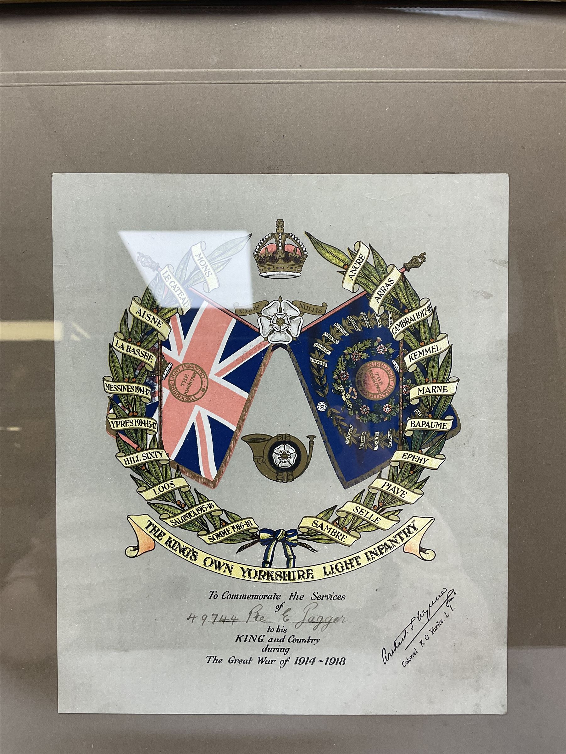 WW1 chromolithograph print of a battle scene with French and German soldiers in a wood, entitled 'De Wereldoorlog 1914-18 Slag Van Houthulst' 35 x 49cm, oak frame; and a framed WW1 regimental testimonial to 49744 Pte. E. Jagger KOYLI, gilt frame (2)