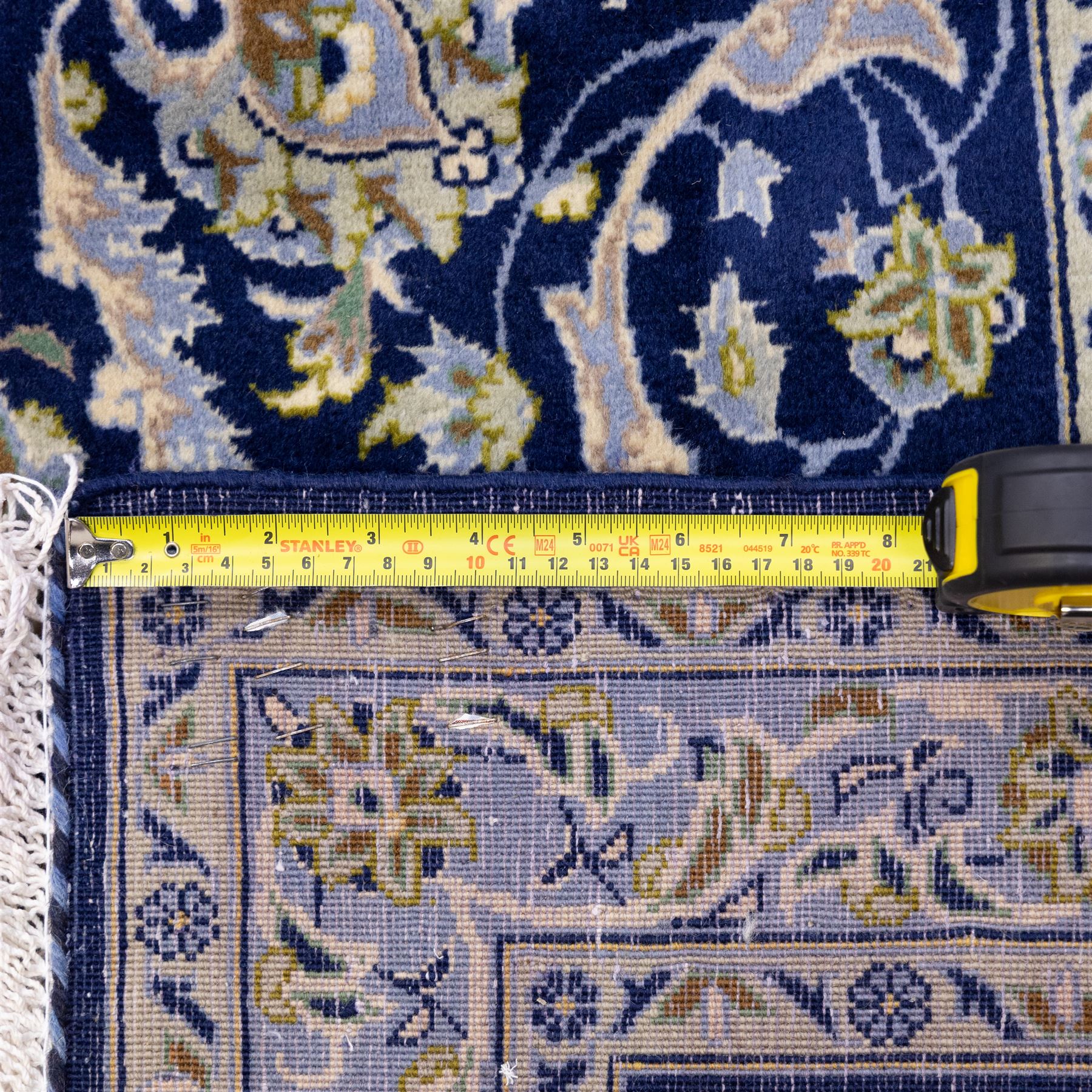 Central Persian Kashan hand-knotted rug, deep blue all-over field, finely decorated with dense scrolling floral sprays, palmettes, and flowering vines in ivory, soft gold, and pale green tones, enclosed by a multi-band floral border with corresponding guard stripes, with cotton fringe ends, signed Shah Abassi Workshop 