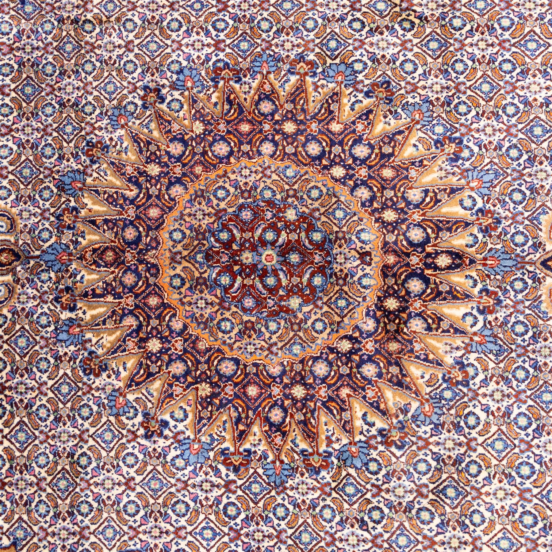 North Eastern Persian Moud hand-knotted carpet, field with central lobbed medallion with radiating serrated palmettes and spandrels in a densely worked all-over ground of small floral rosettes and geometric blossoms within a wide floral border flanked by multiple guard borders in a palette of indigo blue, ivory, terracotta, turquoise, and muted gold, with cotton fringe ends 