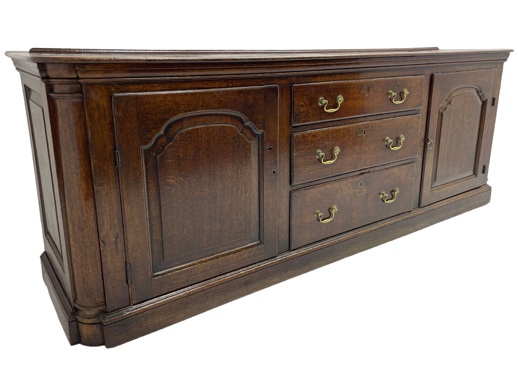 George III oak dresser base, rectangular top with rounded corners over moulded frieze rail, canted corners with turned quarter columns, fitted with three drawers with moulded edges flanked by two cupboards, enclosed by ogee arched fielded panelled doors, panelled sides, moulded plinth base
