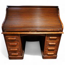 Early 20th century oak twin pedestal roll top desk, tambour roll enclosing small drawers and pigeon holes, fitted with seven drawers, on plinth base 
