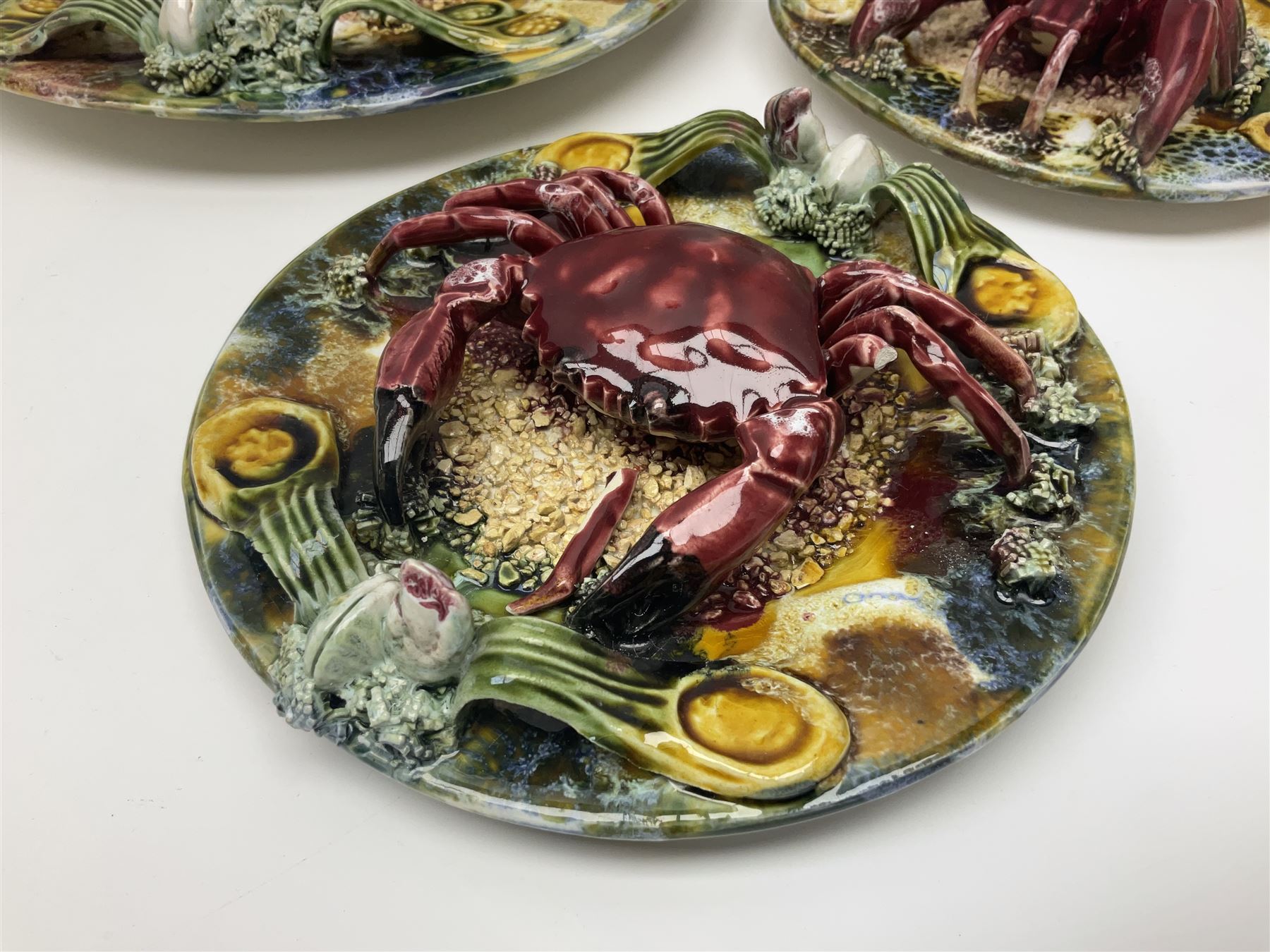 Five 20th Century Portuguese Palissy style Majolica wall plates, all depicting crustaceans to the centre modelled in relief surrounded by encrustations and shells, both with impress marks beneath, largest D29cm