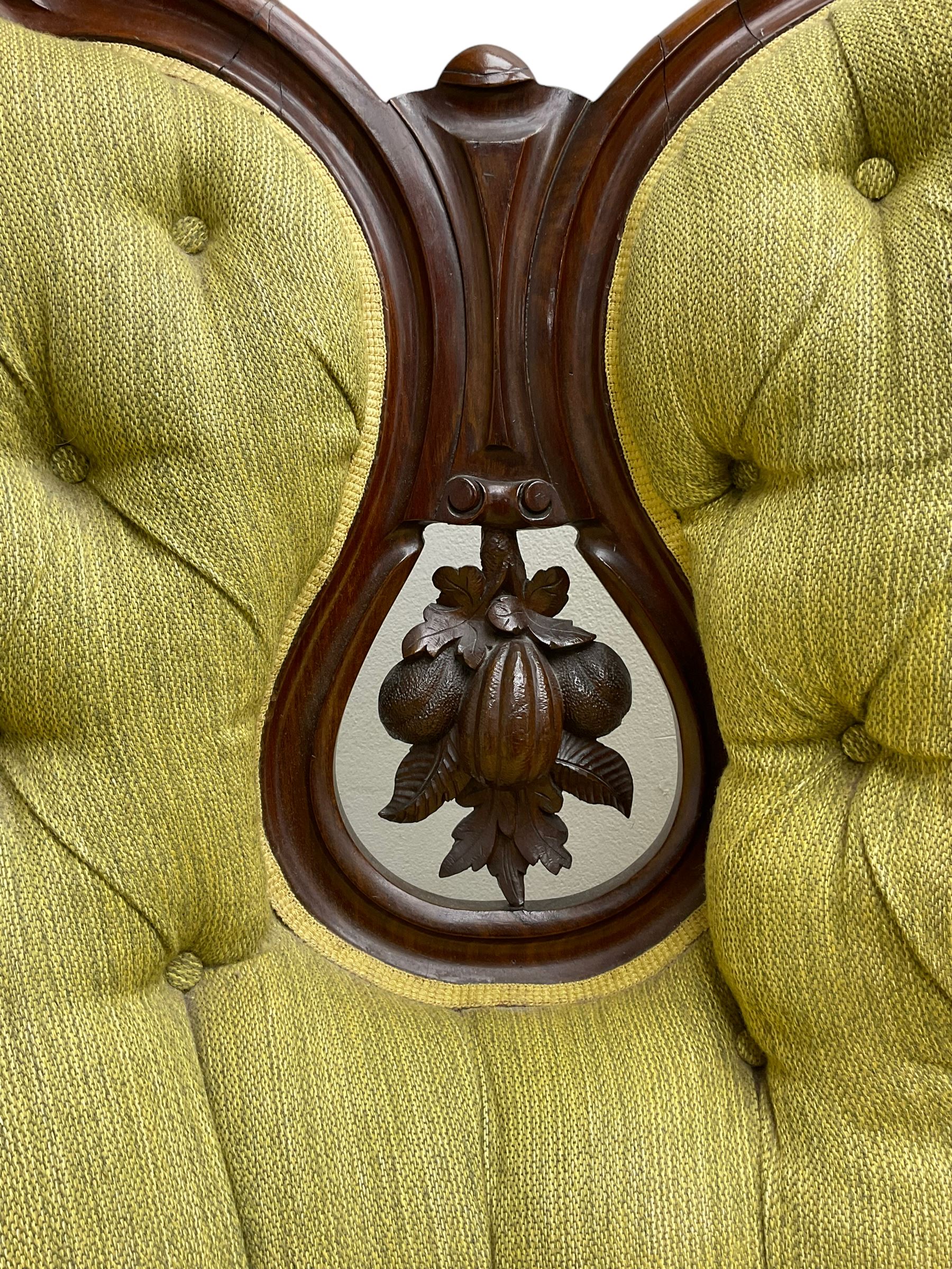Victorian walnut settee, triple back with pierced and scroll-carved cresting rails over carved fruit and foliage decoration, upholstered in buttoned green fabric, serpentine seat and carved apron, on cabriole feet