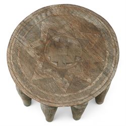 African Nupe carved tribal stool, the rounded top with repeating incised decoration and rope-edge border, supported by ten tapered legs D37cm