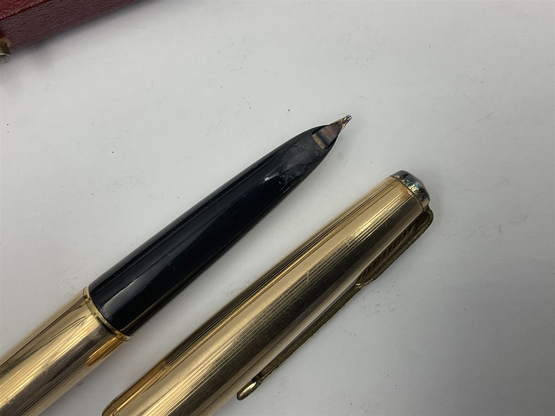 Three rolled gold Parker fountain pens, comprising an example with a gold nib marked 14K 585 and barrel with a shell stamp, a Parker 61 fountain pen with inset gold arrow to the nib, and another similar, all with striated decoration and arrow clips to the caps, L13cm, one with box