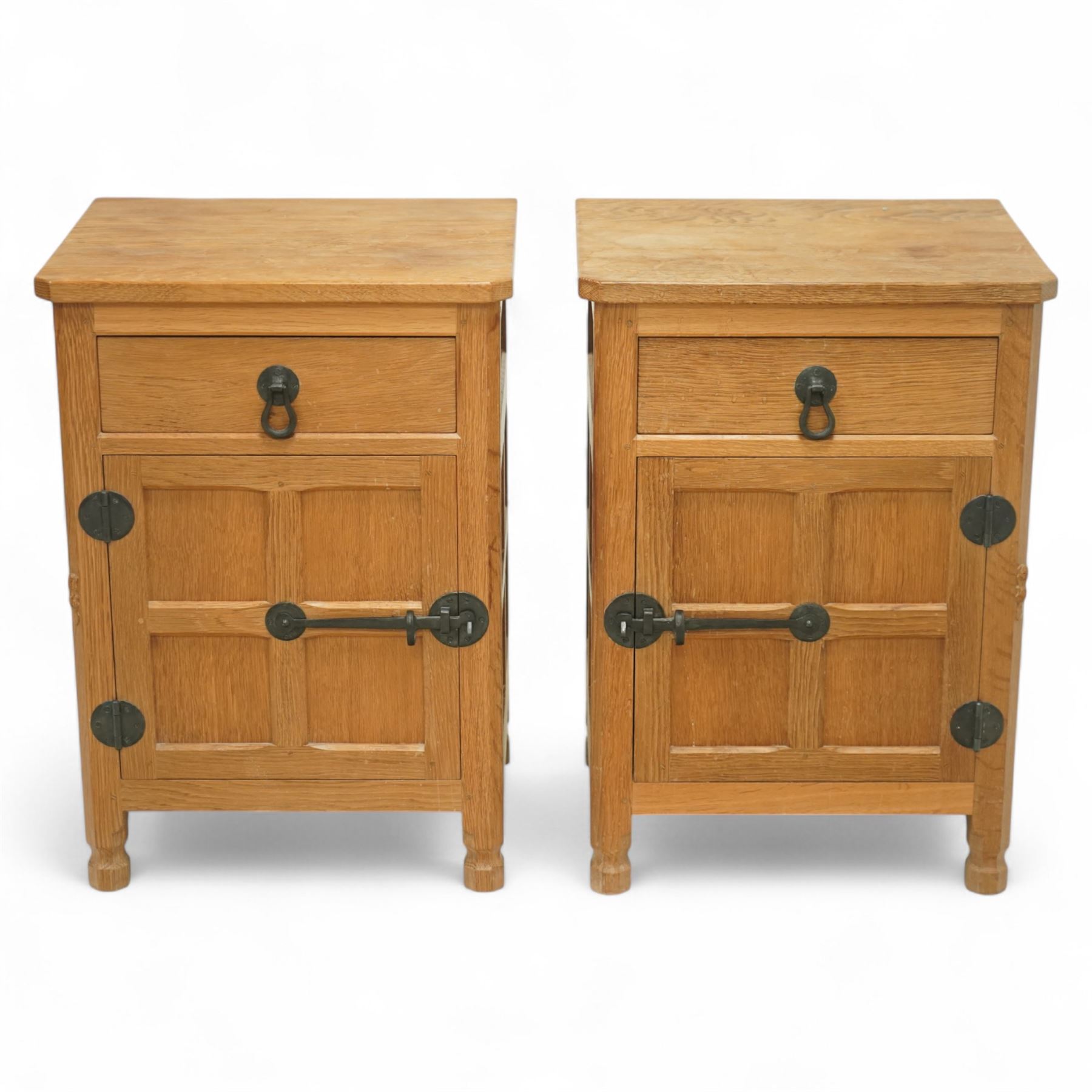 Beaverman - pair of oak bedside cabinets, each with plain rectangular top over single drawer and cupboard below with fielded panels and wrought iron hardware, with signature carved beaver, by the workshop of Colin Almack, Thirsk