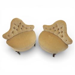 20th century pair of bedroom chairs upholstered in buttoned taupe velour, each of slipper chair form with low wraparound back and deep seat, the backs button tufted with padded wings, raised on turned front supports with castors
