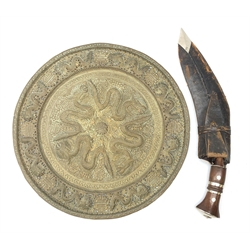 An Eastern metal wall charger, of circular form decorated in relief with dragons and auspicious symbols, with pieced outer rim, D40.5cm, together with a modern leather sheathed kukri knife.
