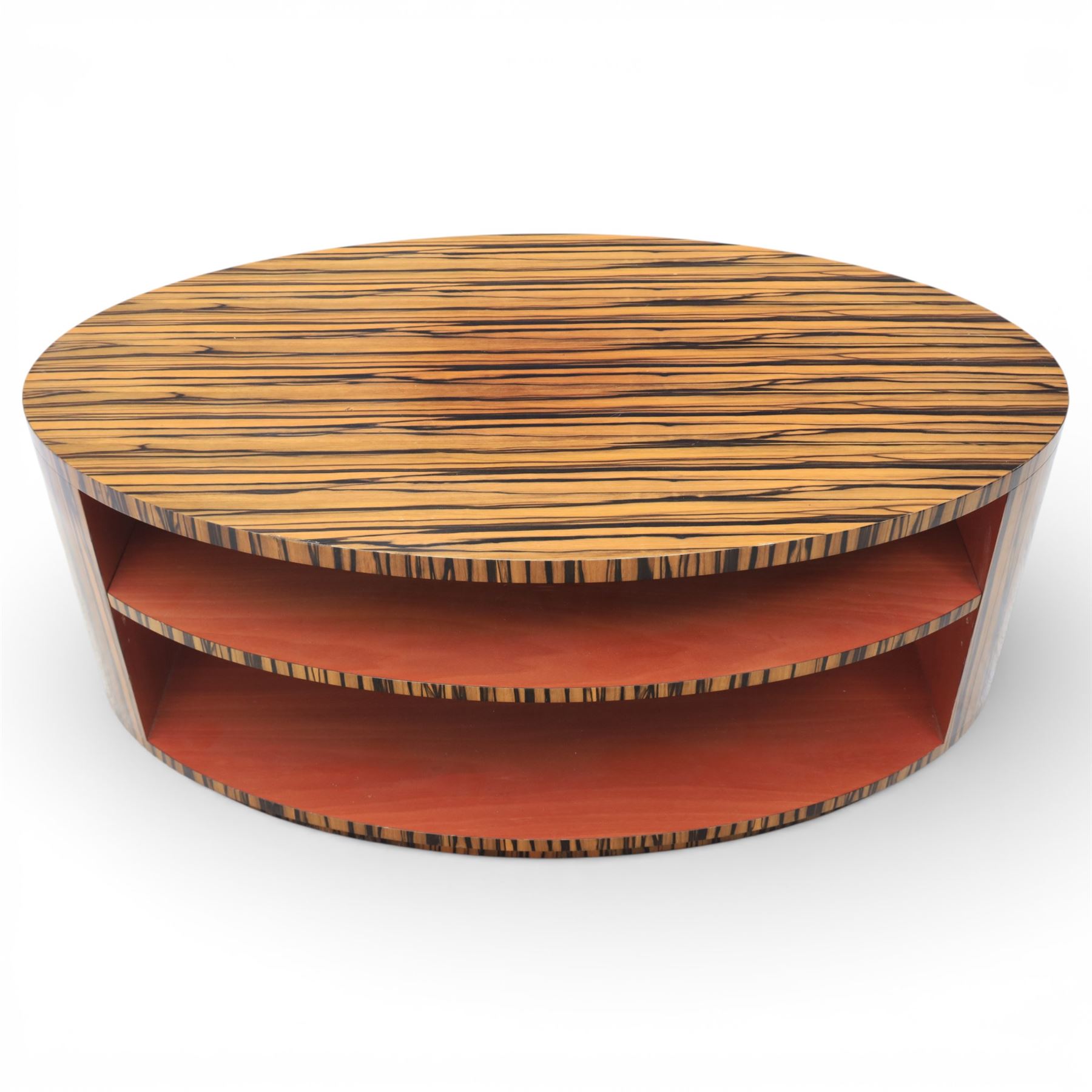 Toby Winteringham - Mid 20th century zebra wood coffee table, oval top with book matched striped veneers over two open tiers painted red, the curved end supports and continuous plinth base veneered to match, recessed plinth base 