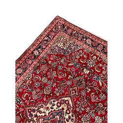 Persian red ground Kashan rug, the field decorated with trailing plant motifs, the guarded border decorated with scrolling foliate and flower heads
