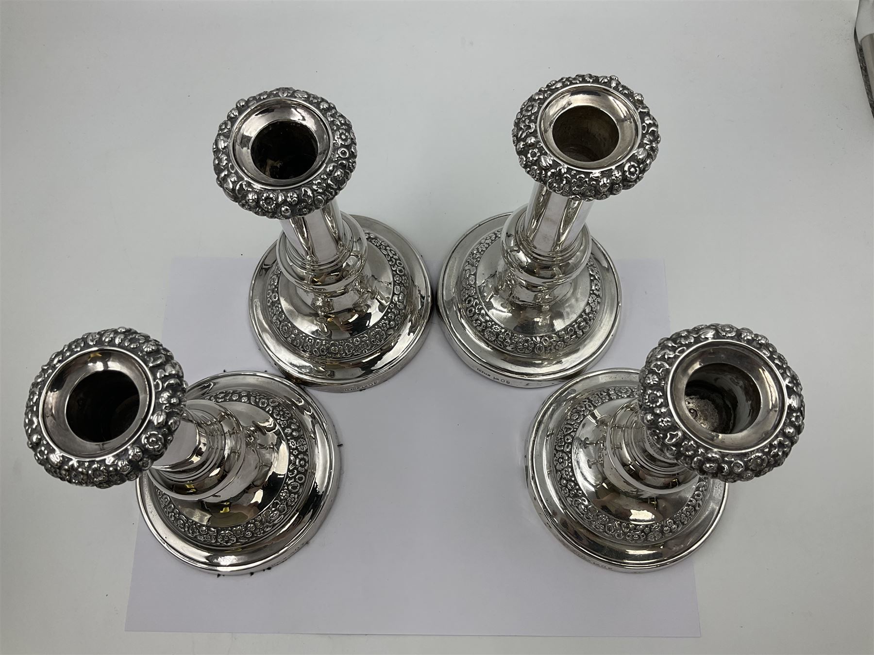 Four George III silver candlesticks, each upon knopped stem and weighted circular stepped foot, the foot and removable sconce repousse decorated with a band of flower heads, hallmarked to sconce and foot Thomas & John Settle, Sheffield 1820, H17.5cm
