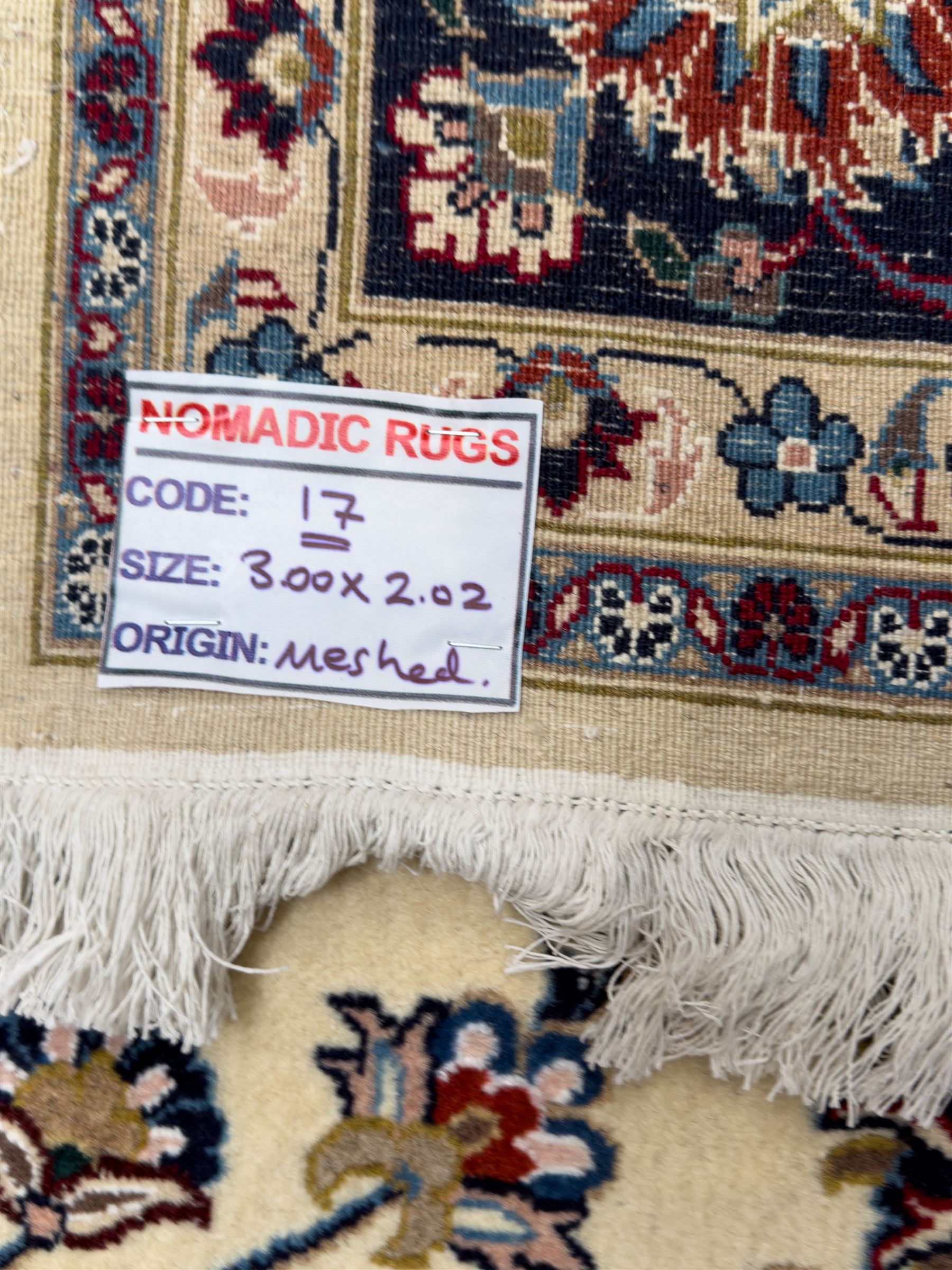 Northeastern Persian Meshed hand-knotted rug, ivory ground with an overall design of scrolling vines, palmettes, and rosettes in an indigo palette, soft blues, and madder, framed by a deep indigo border of lotus palmettes and flowerheads between multiple guard borders, 300cm x 202cm