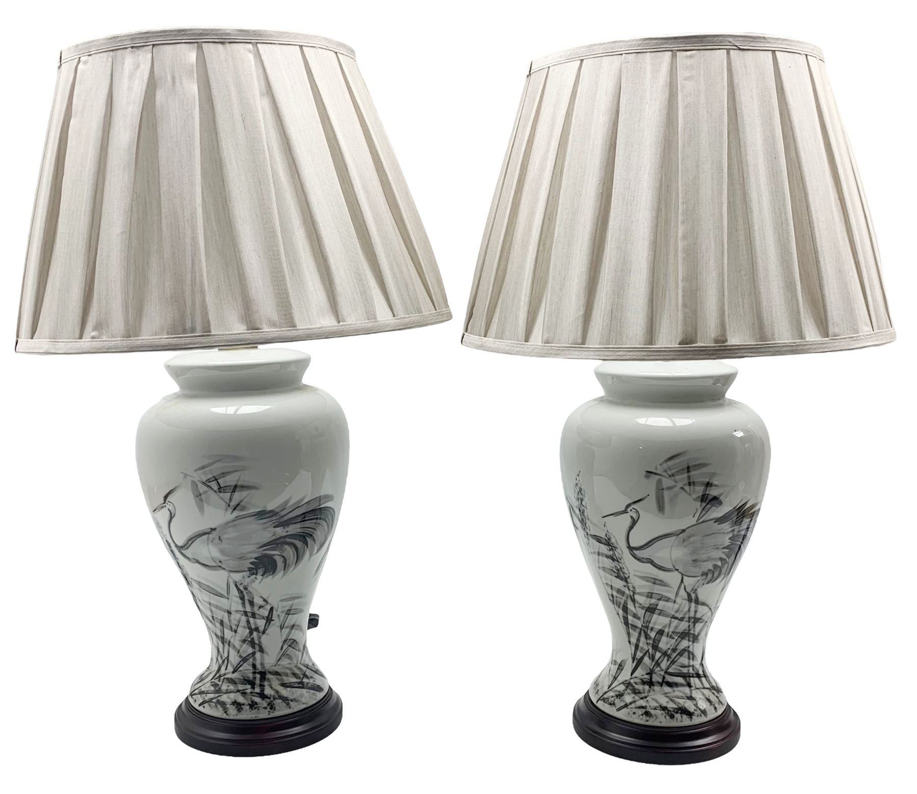 Pair of Chinese porcelain table lamps, each of inverted baluster form, decorated with wading Herons amongst reeds against a plain ground, raised upon circular hardwood base, H66cm including shade 