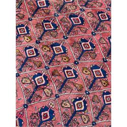 Persian Ardakan crimson ground rug, the field divided by lattice and decorated with stylised tree of life motifs, the border decorated with geometric flower heads, within guard stripes 