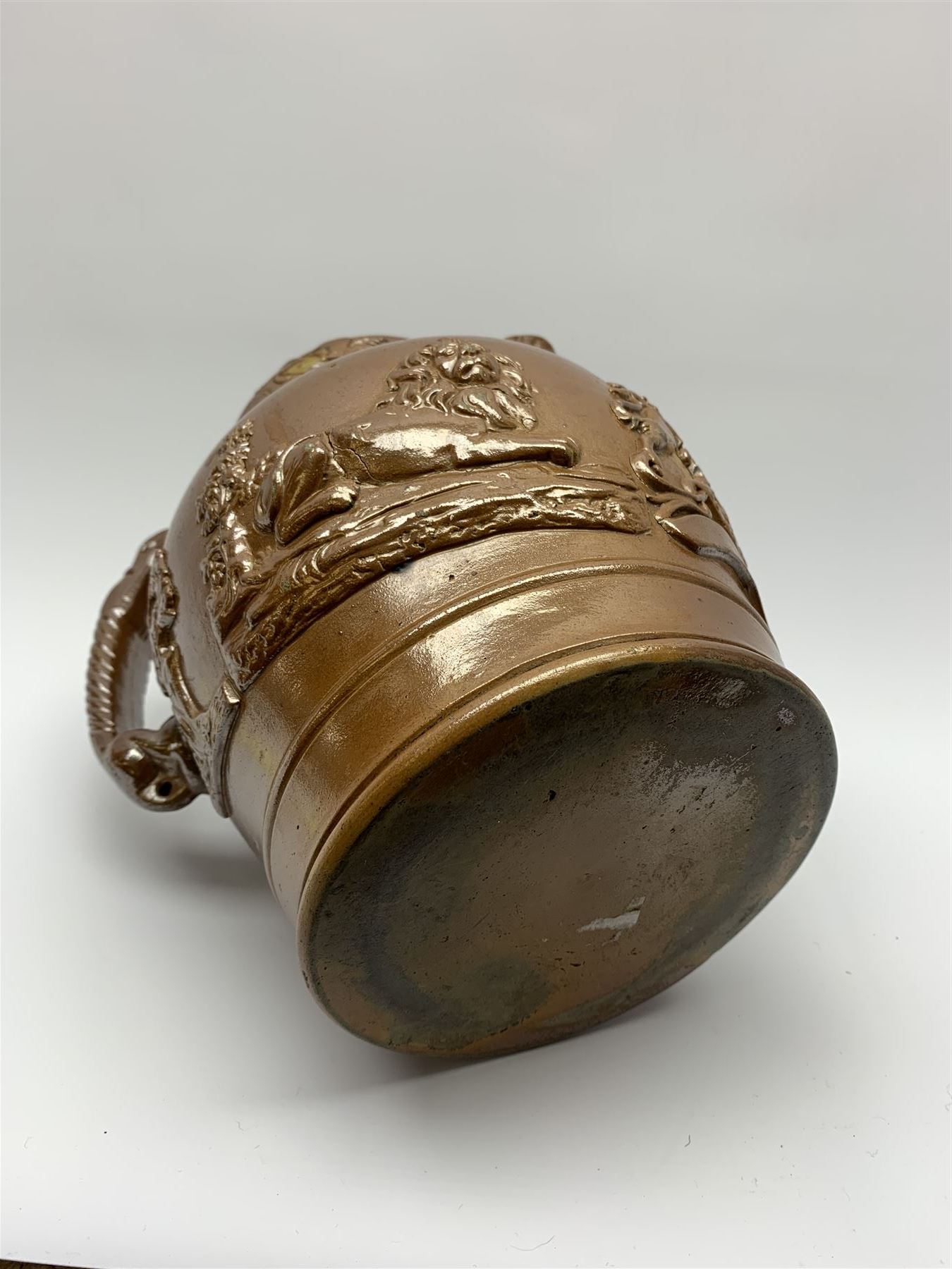 19th century salt glazed stoneware jug, with mask spout and greyhound modelled handle, the body decorated in relief with Royal Coat of Arms flanked by lions, the rim with the flowers of the union, roses, thistles and shamrocks, H26.5cm