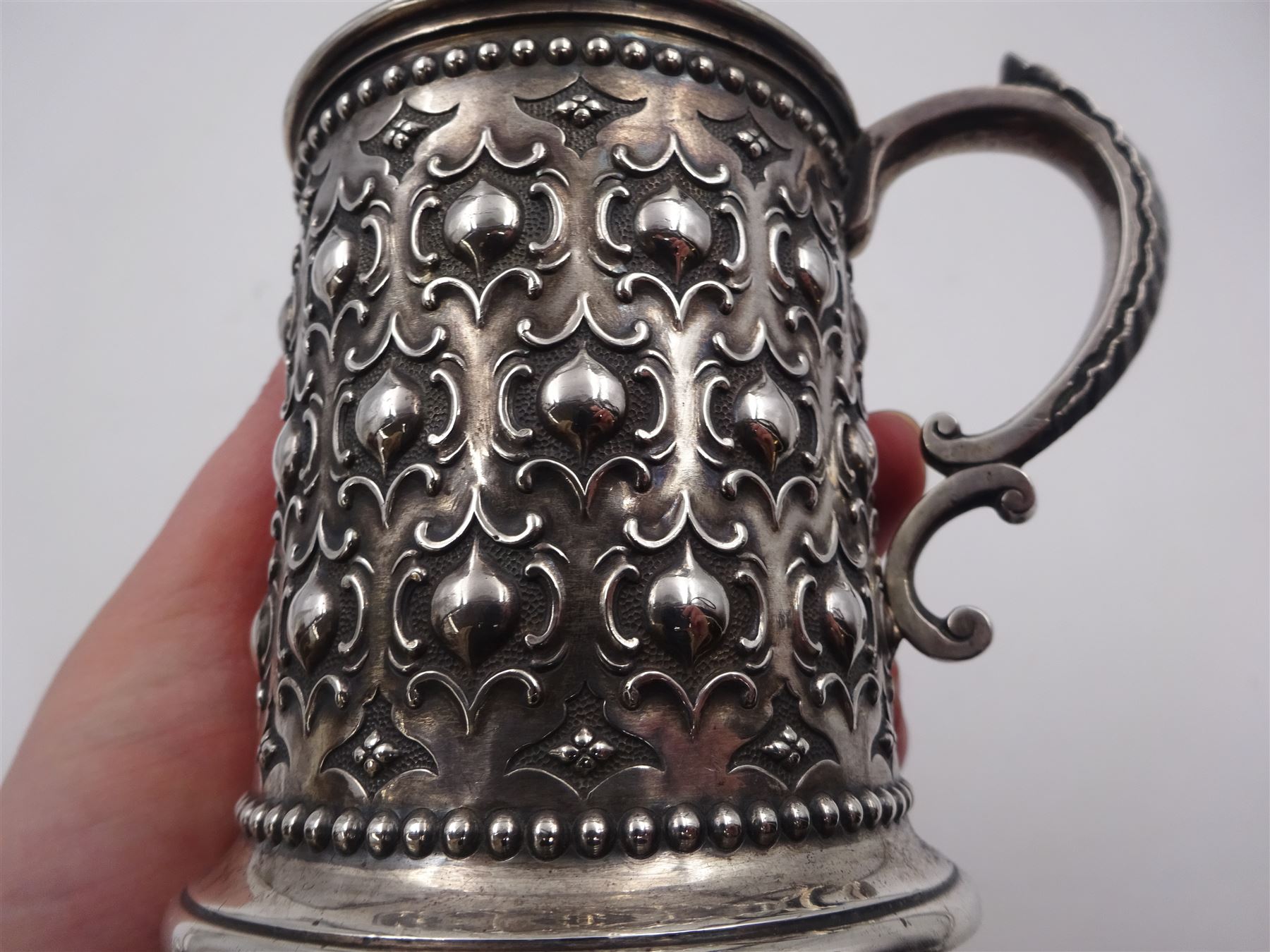 Victorian silver christening mug, with repousse and chased scroll and bead decoration, lozenge shaped cartouche engraved with monogrammed initials and acanthus capped C scroll handle, hallmarked Robert Hennell III, London 1861, H9.3cm