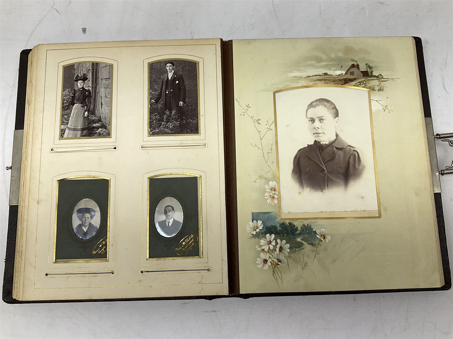 Victorian leather bound photo album, the interior leaves containing apertures of various sizes and shapes of portraits surrounded by printed floral designs, H28cm