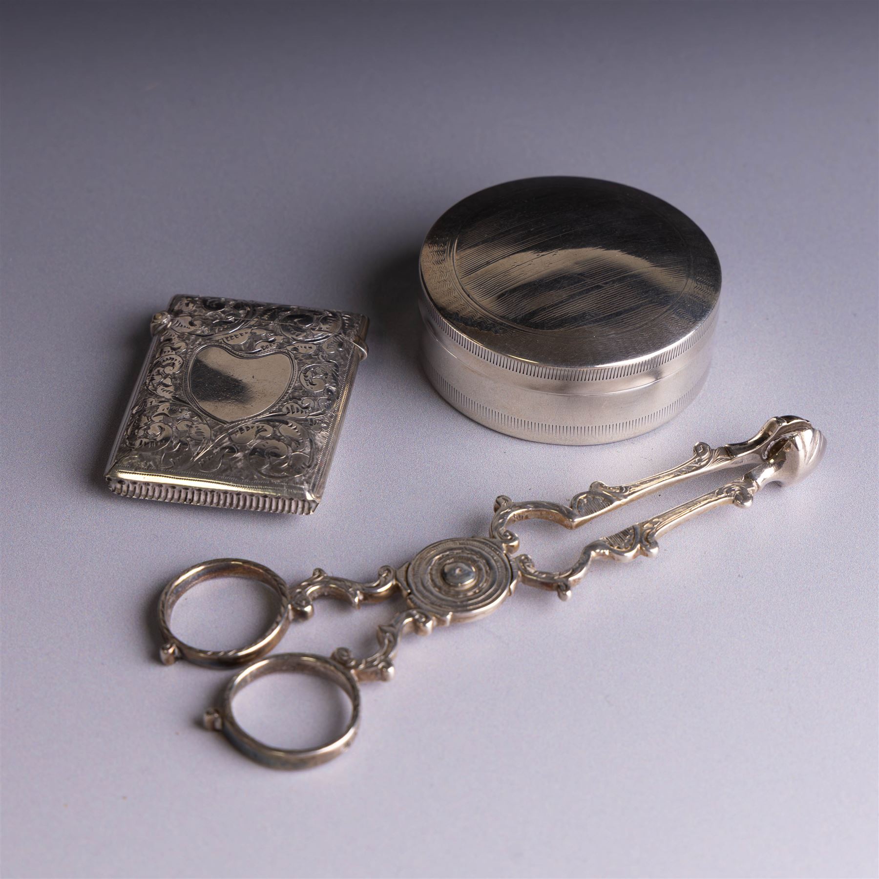 1920s silver lidded box, of circular form with engine turned decoration, hallmarked Stokes & Ireland Ltd, Chester 1920, together with a pair of Victorian silver sugar nips, hallmarked George Unite, Birmingham 1870, and a Victorian silver vesta case, box D5.5cm