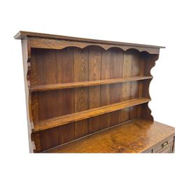 Late Victorian oak dresser, plate rack over three drawers and three cupboards, the panelled doors carved with floral motifs