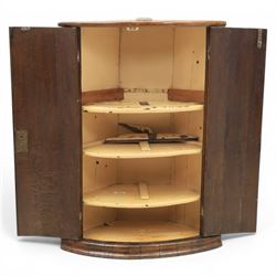 George III oak cylindrical corner cupboard, bow fronted doors revealing a painted shelved interior, brass escutcheons  and hinges, raised on a moulded plinth base