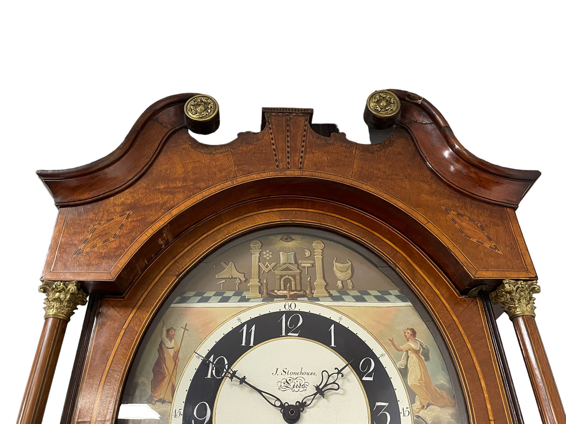 John Stonehouse of Leeds - mahogany 8-day longcase clock with a painted oval dial c1830, hood with a swans necked pediment and profuse contrasting inlay to both the hood and case, oval hood door with flanking pilasters and Corinthian capitals, conforming case with canted corners and short triple spire door, broad plinth with matching inlay and canted corners on shallow base, dial depicting masonic regalia, symbols, and pictorial depictions of the humanities, faith, hope, charity and righteousness, black chapter with white roman Arabic’s, date recorder and matching “crown” hands, dial pinned to a rack striking movement with a recoil anchor escapement, striking the hours on a coiled underslung gong. With weights and gridiron pendulum. 
This clock case is of large, impressive dimensions and was almost certainly commissioned for a large masonic lodge in Leeds, a rare and unique example.
