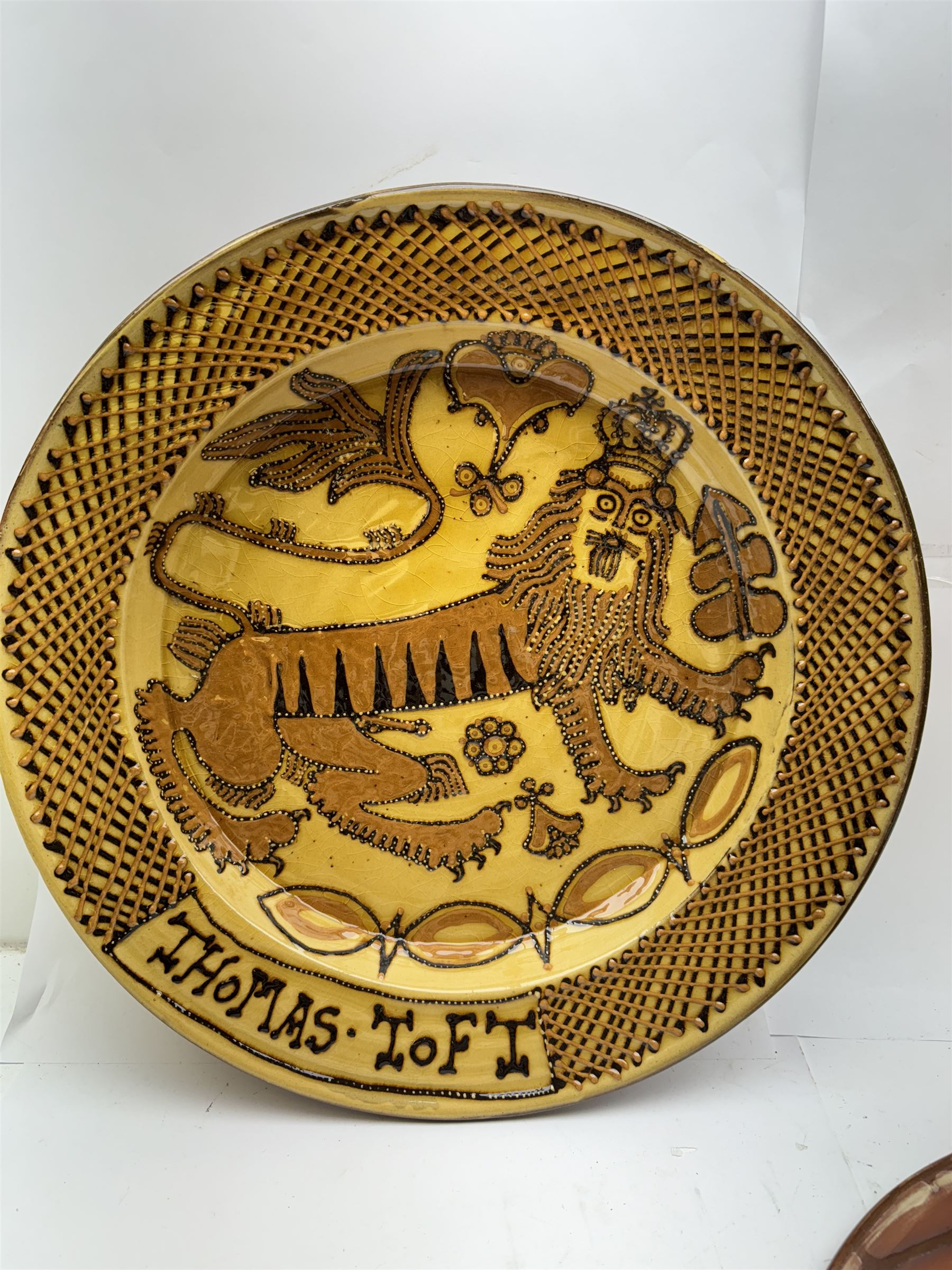 John Hudson: Large slipware charger in the style of Thomas Toft by John Hudson of Mirfield Pottery, decorated with the lion supporter taken by Toft from the Royal Arms, incised marks verso, D 44cm.
