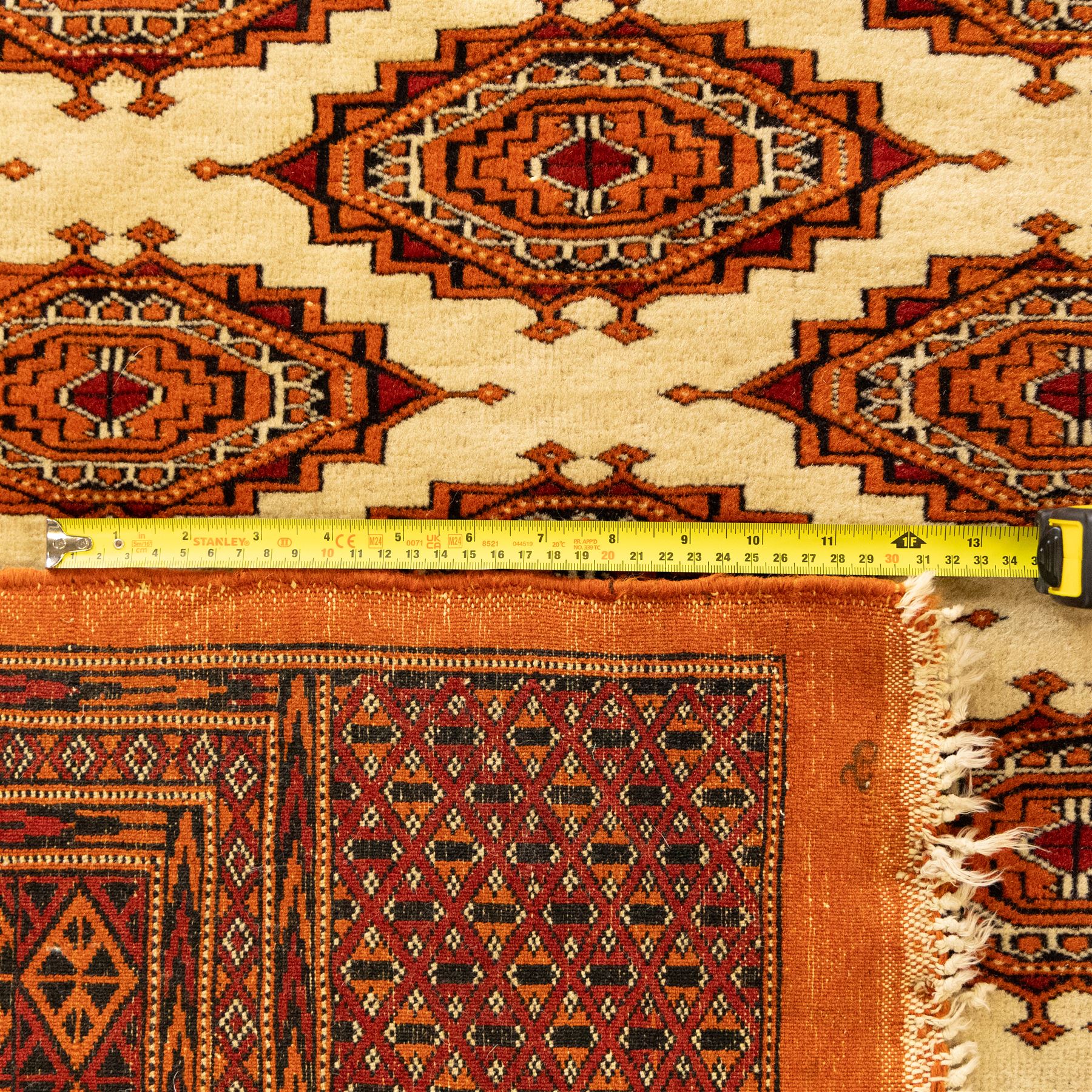 Three rugs,  comprising a Baluch rug in crimson ground, 179x97cm, a Tekke Bokhara rug in crimson ground, 201x132cm, and a Bokhara rug in ochre ground, 125x175cm 