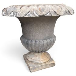 Set of three 19th century weathered carved sandstone garden urns of Neoclassical campana form, the broad everted rim carved with pointed egg-and-dart motifs, above a plain waisted bowl with gadrooned underbelly, on moulded rope-twist socle and square plinth base