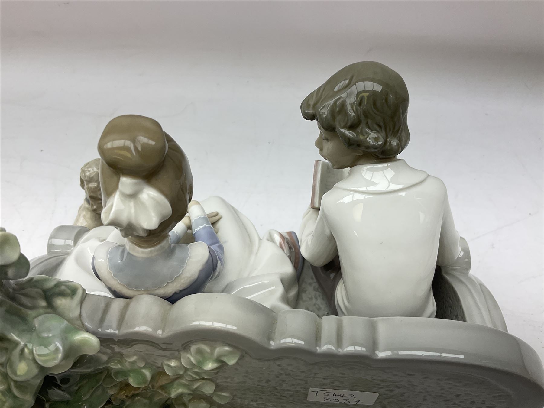 Lladro figure, Poetry of Love, modelled as a boy seated reading from a book next to a girl on garden bench with a dog at her feet, sculpted by Regino Torrijos, with original box, no 5442, year issued 1987, year retired 1998, H22cm