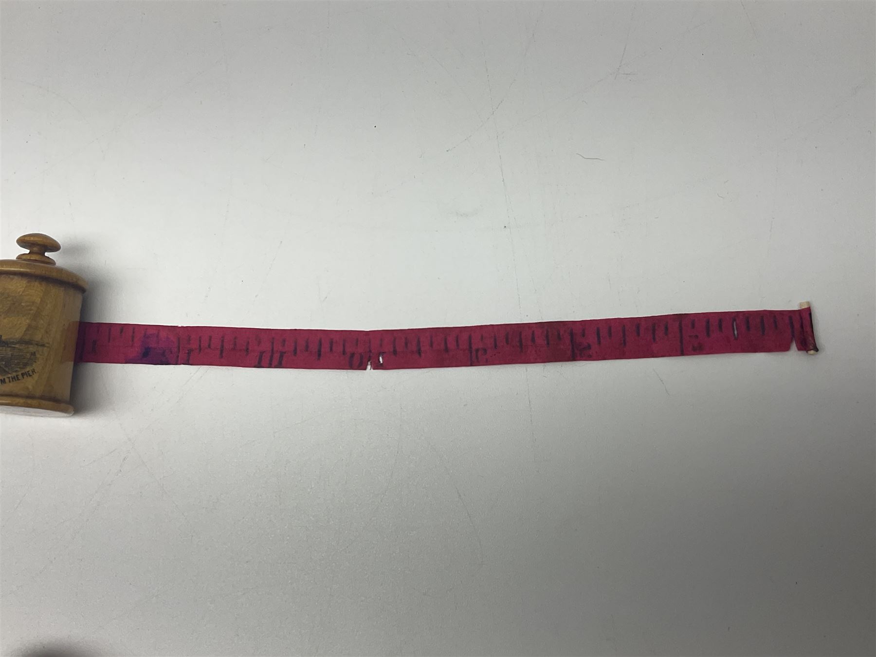 Six sewing related Mauchline ware comprising an oval reel box with internal label for Clark & Co's, tape measure, pin case and three thimble holders of ovoid form 