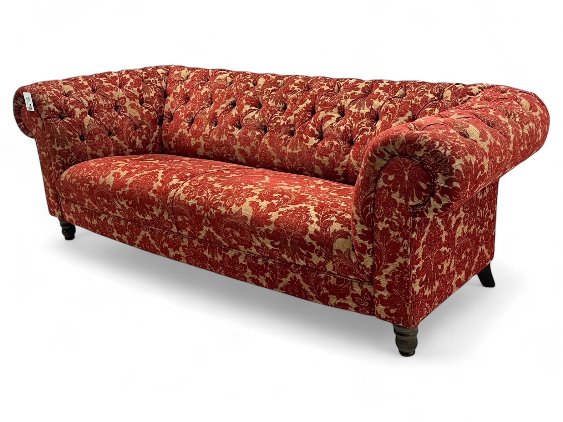 Late 20th century upholstered Chesterfield sofa, in red damask floral fabric, with deep buttoned back and arms, scrolled arms at equal height to back, on turned front supports