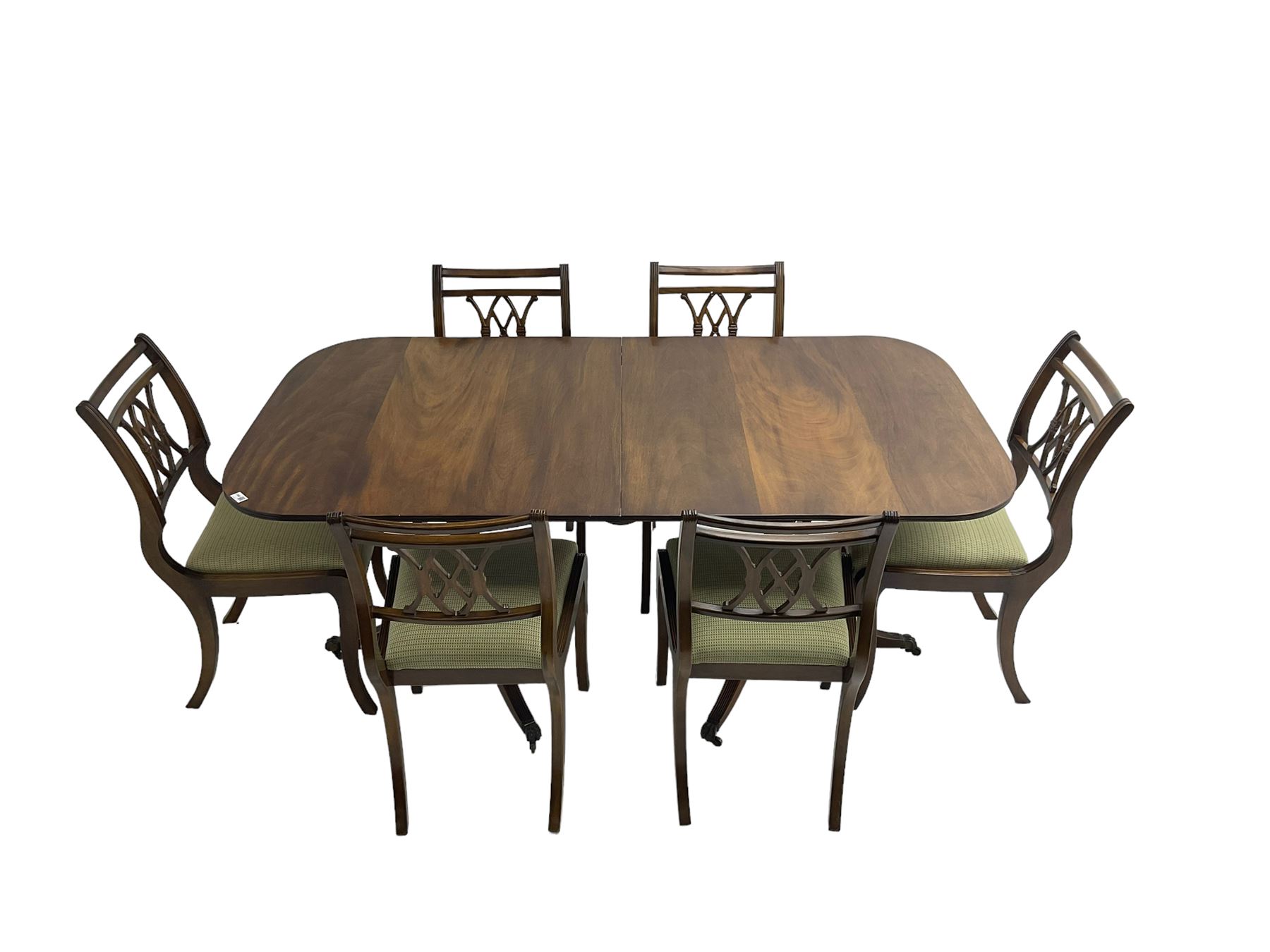 Regency design mahogany twin pedestal dining table, rectangular top with reeded edge, acanthus carved turned column terminating in reeded tripod base with hairy paw feet and castors (W172cm D92cm H75cm) and set eight (6+2) Regency design mahogany dining chairs, pierced back with scroll design, seat upholstered in patterned laurel green fabric, raised on reeded sabre supports (W48cm H88cm)