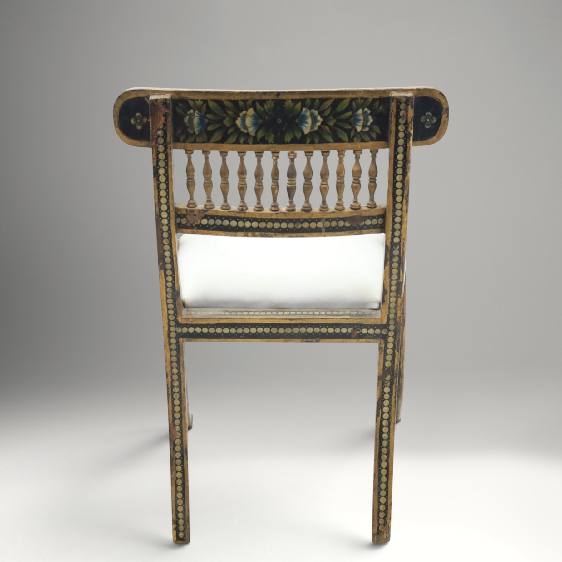 Early 20th century Anglo-Indian painted and inlaid armchairs, each with shaped top rail decorated with polychrome floral motifs above turned spindle galleries, shaped open arms and upholstered seats, on square supports with similar painted decoration